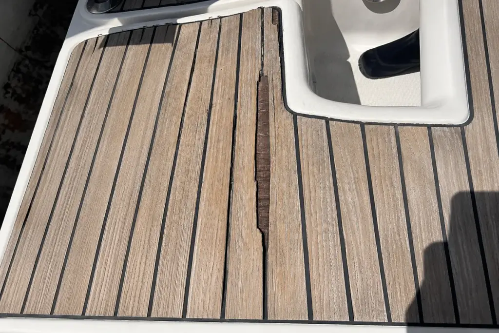Defektes Teak auf einem Bootsdeck mit deutlich sichtbarer Delaminierung.